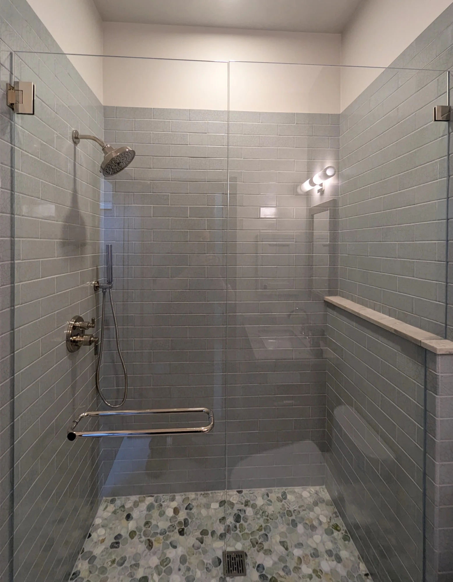 Tiled walk-in shower with a glass enclosure and a pebble mosaic floor