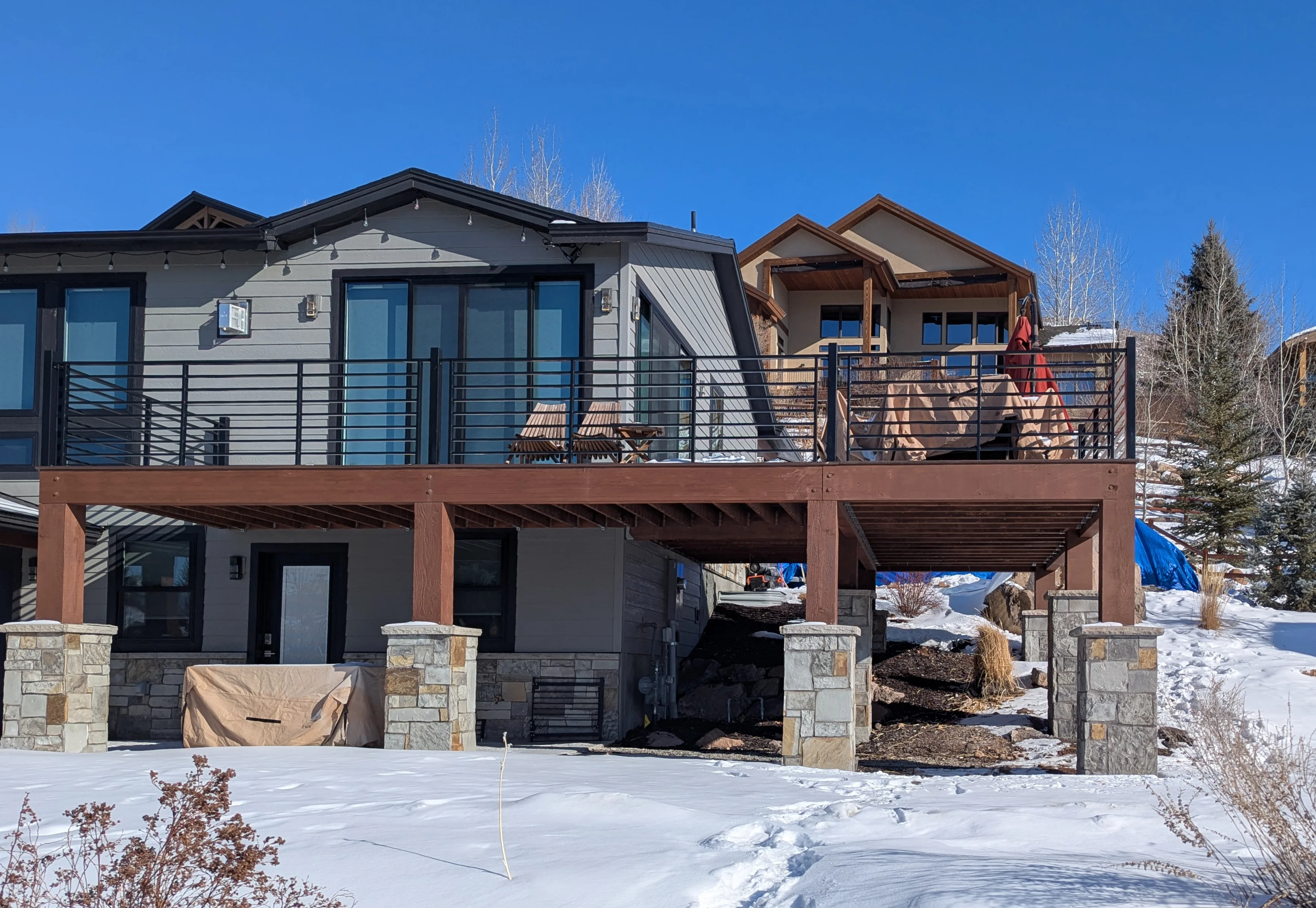 Elevated deck addition on a mountain home, carried on structural columns set on stone piers