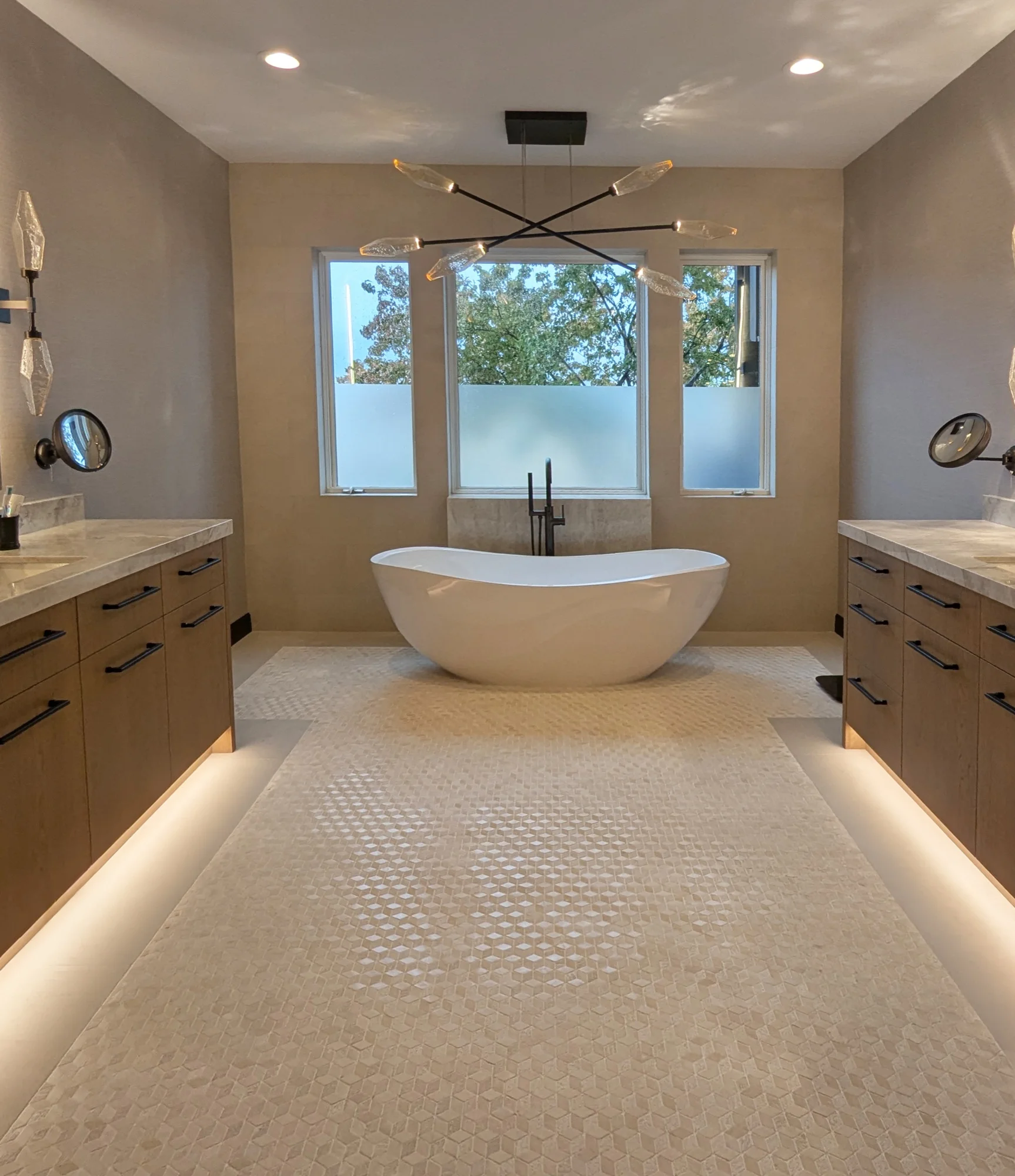 Primary bathroom with a freestanding soaking tub between two vanities